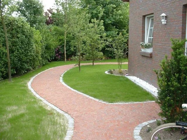 Roter Pflasterweg entlang eines Wohnhauses.